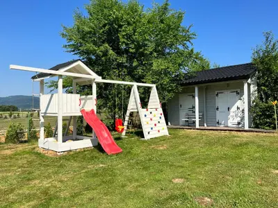 a playground with a slide in a yard at Babiogórska Perełka w skandynawskim stylu z sauną i kominkiem in Jordanów