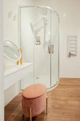 a bathroom with a glass shower and a stool at Cozy Apartment in Old Town in Kraków