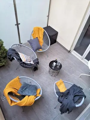 three wicker chairs and a table on a balcony at Old Town Apartment in Kraków