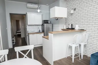 a kitchen with white cabinets and white stools at Old Town Apartment in Kraków