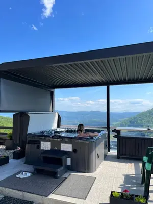 a person in a hot tub on a patio at Domek w Chmurach II in Kicznia