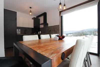 a dining room with a wooden table and white chairs at Domy Pod Babią in Zawoja