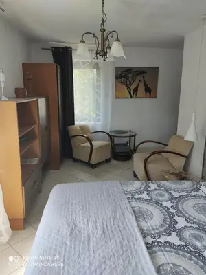 a bedroom with a bed and chairs and a window at Pokój w domu z dużym ogrodem in Kraków