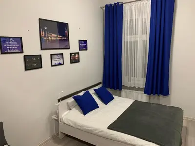 a bedroom with a bed with blue curtains and a window at Discover Cracow APARThostel in Kraków