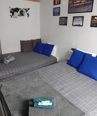 two beds in a room with blue pillows and a couch at Discover Cracow APARThostel in Kraków