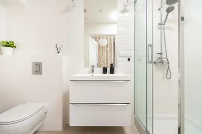 a white bathroom with a sink and a shower at Modern Centrally Located Apartments - by Upstairs in Kraków