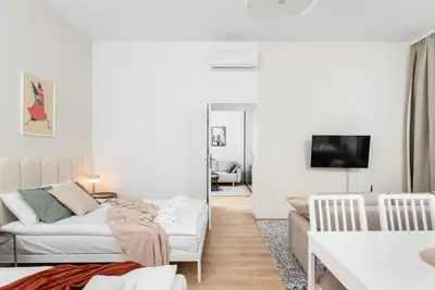 a white living room with a couch and a table at Modern Centrally Located Apartments - by Upstairs in Kraków
