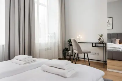 a white bedroom with two beds and a desk at Modern Centrally Located Apartments - by Upstairs in Kraków
