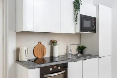 a white kitchen with a sink and a microwave at Modern Centrally Located Apartments - by Upstairs in Kraków