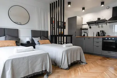 a bedroom with two beds and a kitchen at Studio Kolberga Kraków in Kraków