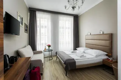 a bedroom with a bed and a couch and a television at G12 Aparthotel in Kraków