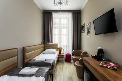 a hotel room with two beds and a flat screen tv at G12 Aparthotel in Kraków