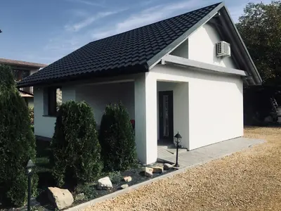 a small white house with a black roof at DOMEK U MARKA Zator in Przeciszów