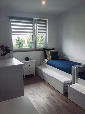 a bedroom with a bed and two windows at DOMEK U MARKA Zator in Przeciszów
