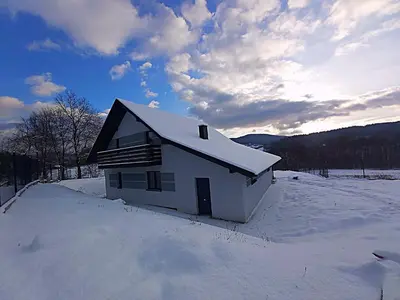 a small white house with snow on top of it at Sarnie wzgórze Sucha Beskidzka sauna jacuzzi in Kuków
