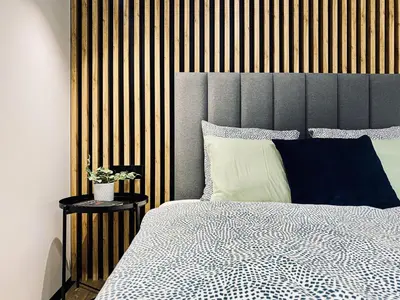 a bedroom with a large bed with a wooden headboard at Apartment next to Cracow Eye, Vistula Boulevards in Kraków