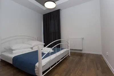 a bedroom with a white bed with a blue blanket at Lenzo Apartments Wieliczka in Wieliczka