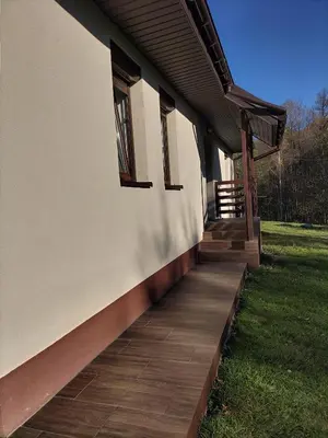 a building with a wooden walkway next to a yard at Zielony Zakątek in Złota