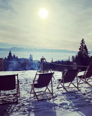 two chairs in the snow with the sun in the background at Domek w Górach- Bacówka u Dudka in Nowy Targ