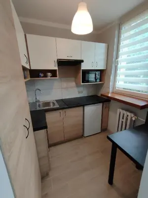 a kitchen with white cabinets and a black counter top at Apartament Cichy Kącik Zator tylko 1km od ENERGYLANDII in Zator