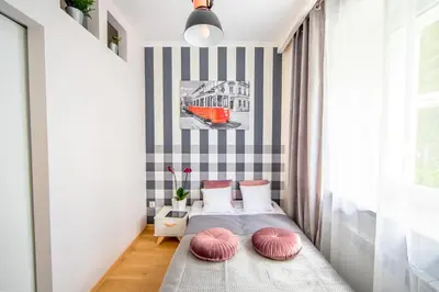 a small bedroom with a bed with pink pillows at Cracowapart Ignacio A in Kraków