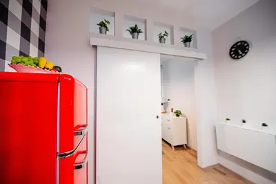 a red refrigerator in a kitchen with plants on a shelf at Cracowapart Ignacio A in Kraków