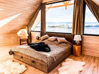 a bed in a room with a large window at Osada Janosika Jacuzzi Drewniany Domek Na Odludziu in Klikuszowa