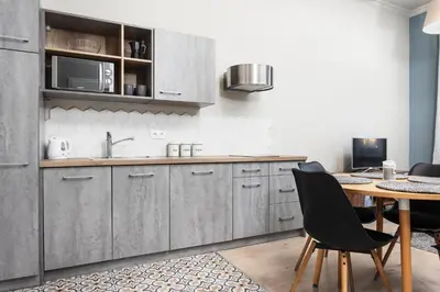 a kitchen with gray cabinets and a wooden table at City of the Kings - Mosaic Apartment in Kraków