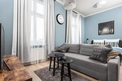 a living room with a couch and a clock on the wall at City of the Kings - Mosaic Apartment in Kraków