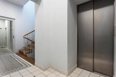 a hallway with a metal door and a staircase at City of the Kings - Mosaic Apartment in Kraków