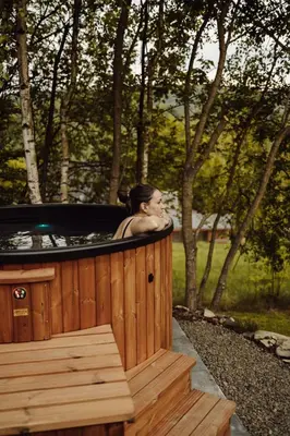 a woman is sitting in a hot tub at Czill-Lokum- klimatyczna chata w Beskidach z balią i sauną in Maków Podhalański