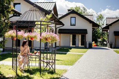 a woman sitting at a table in front of a house at RABA RESORT - Domki i Apartamenty pod Krakowem in Gdów