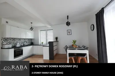 a white kitchen with a table and a dining room at RABA RESORT - Domki i Apartamenty pod Krakowem in Gdów