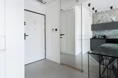 a white hallway with a glass door and a kitchen at Central Apartments by Bed&Bath in Kraków