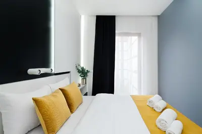 a bedroom with a white bed with yellow pillows at Central Apartments by Bed&Bath in Kraków