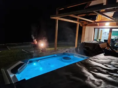 a swimming pool in front of a fire at night at Zacna Chata domek z jacuzzi na wyłączność in Półrzeczki