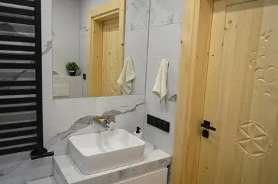 a bathroom with a white sink and a mirror at Zacna Chata domek z jacuzzi na wyłączność in Półrzeczki