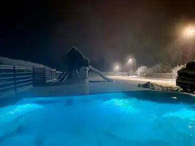 a hot tub covered in snow at night at Zacna Chata domek z jacuzzi na wyłączność in Półrzeczki