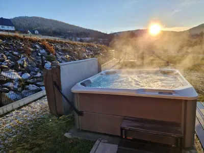 a hot tub with the sun in a field at Zacna Chata domek z jacuzzi na wyłączność in Półrzeczki