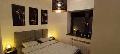 a bedroom with a bed with two lamps and a window at Apartamenty Obidowa in Obidowa