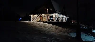 a house lit up at night in the snow at Apartamenty Obidowa in Obidowa