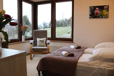 a bedroom with a bed and a chair and windows at Beskid Rose & SPA in Słopnice