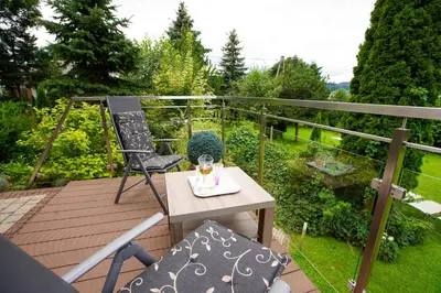 a wooden deck with a table and chairs on a balcony at Beskid Rose & SPA in Słopnice