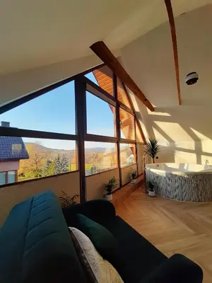 a living room with a couch and a large window at Beskid Rose & SPA in Słopnice