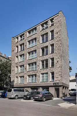 a large brick building with cars parked in a parking lot at HOUSEHOST Apartment: Miodowa 42/30 Street in Kraków