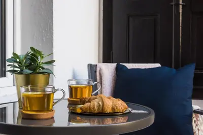 a coffee table with two cups of tea and croissants at Luxury SPA Apartment Old Town Krakow in Kraków