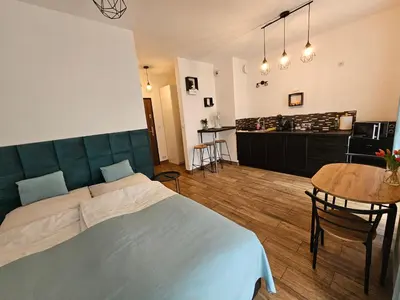a bedroom with a bed and a table and a kitchen at Steam Park Rakowicka Koper Apartment in Kraków