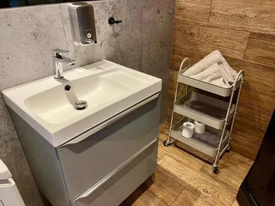 a bathroom with a white sink and a towel rack at Steam Park Rakowicka Koper Apartment in Kraków