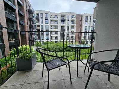 a balcony with two chairs and a table and a building at Steam Park Rakowicka Koper Apartment in Kraków