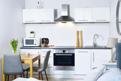 a kitchen with white cabinets and a table with chairs at 21 Floriańska Street Apartments in Kraków